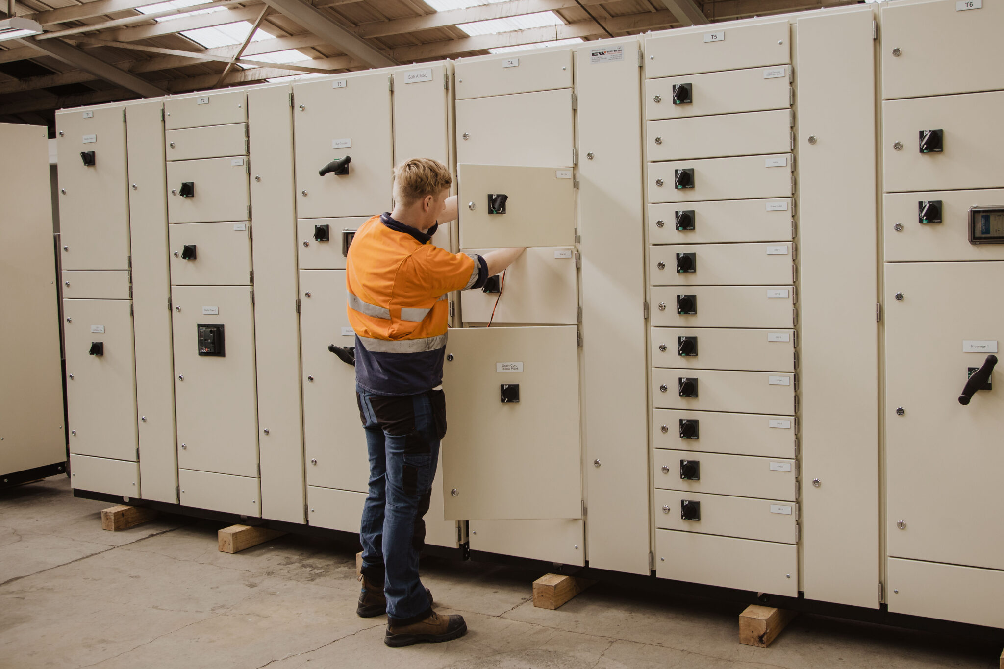 Electrician working on a motor control centre switchboard with multiple compartments at Clive Wilson Switchboards