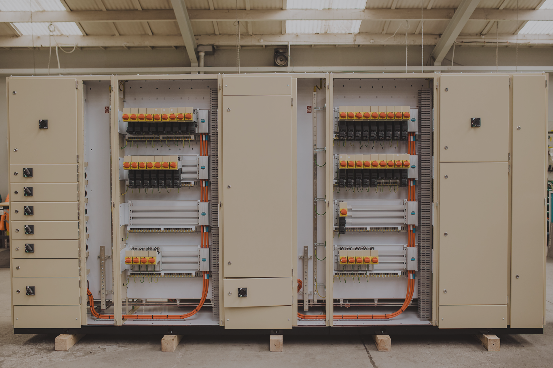 Switchboard group assembly in progress showing multiple electrical panels with circuit breakers and wiring in workshop